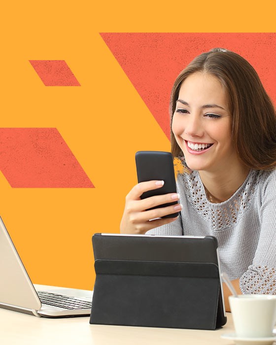 Ragazza alla scrivania che guarda verso il suo smatrphone.