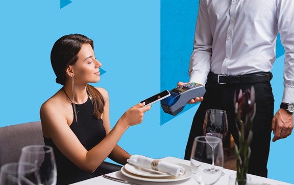 Ragazza sorridente e soddisfatta seduta a un tavolo di un ristorante che paga con carta di credito il conto.